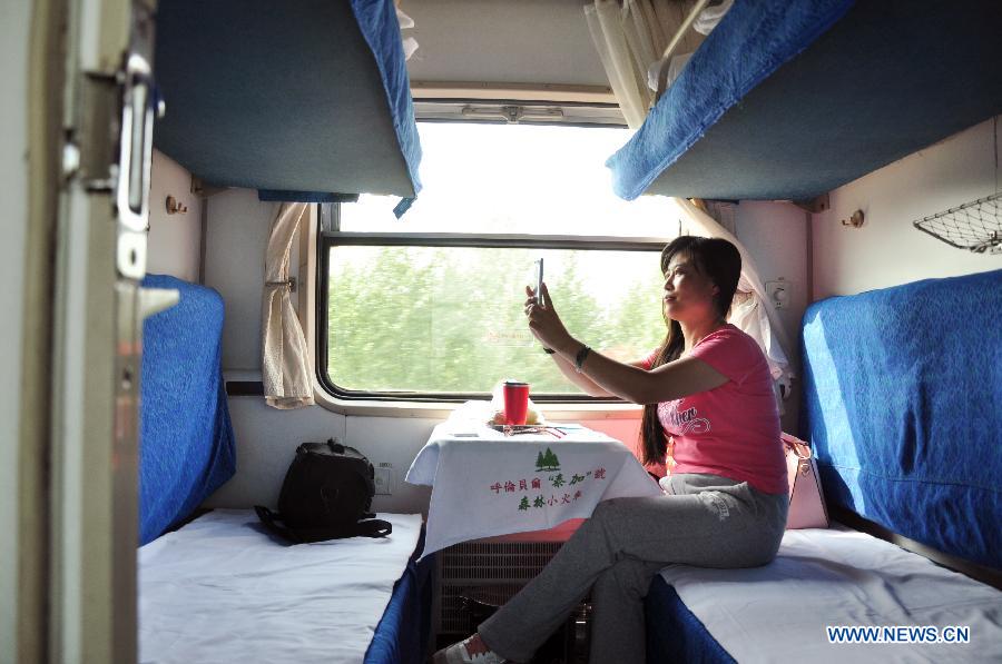 A passenger takes photos on the sightseeing train in Hulunbuir, north China's Inner Mongolia Autonomous Region, July 24, 2015. 