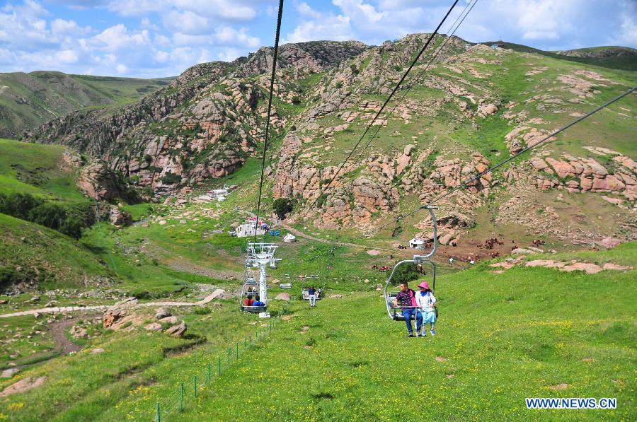 Tourists enjoy the scenery of the grassland near Ulanqab City, north China's Inner Mongolia Autonomous Region, July 24, 2015.