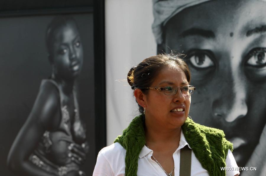 A woman walks past the photographic show 'Infancia' by Spanish photographer Isabel Munoz, in the Heroic Youth Road of the Forest of Chapultepec, in Mexico City, capital of Mexico, on July 26, 2015. 