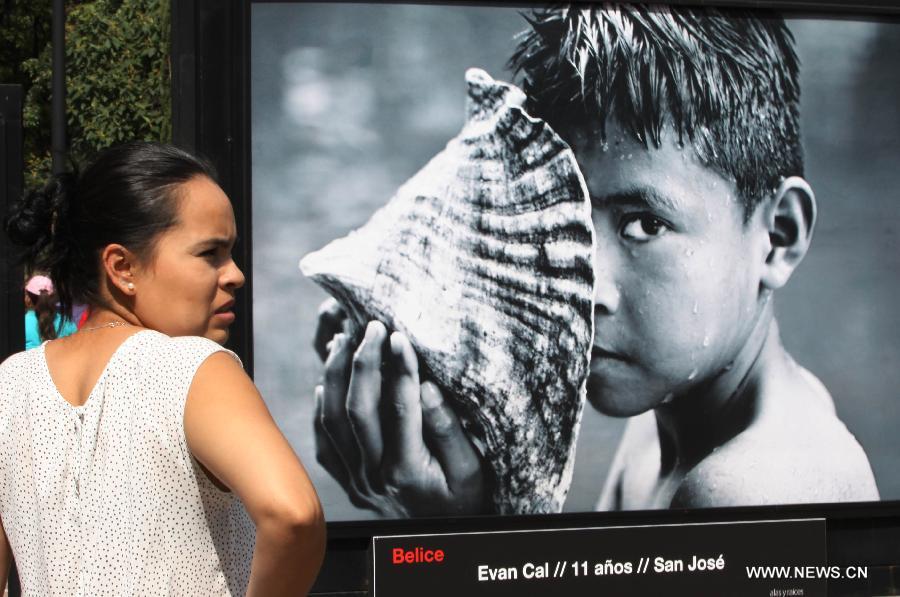 A woman watches the photographic show 'Infancia'by Spanish photographer Isabel Munoz, in the Heroic Youth Road of the Forest of Chapultepec, in Mexico City, capital of Mexico, on July 26, 2015.