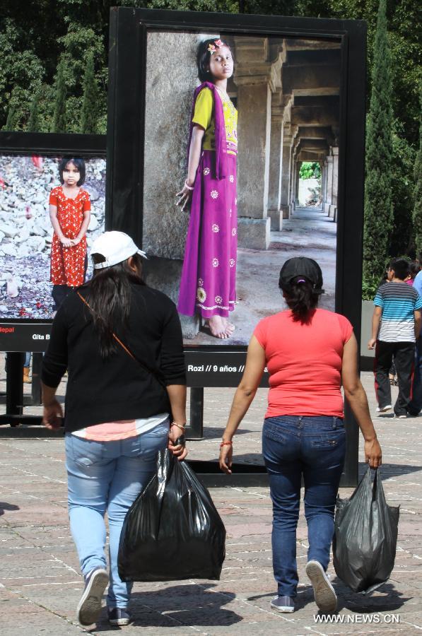 People watch the photographic show 'Infancia' by Spanish photographer Isabel Munoz, in the Heroic Youth Road of the Forest of Chapultepec, in Mexico City, capital of Mexico, on July 26, 2015. 