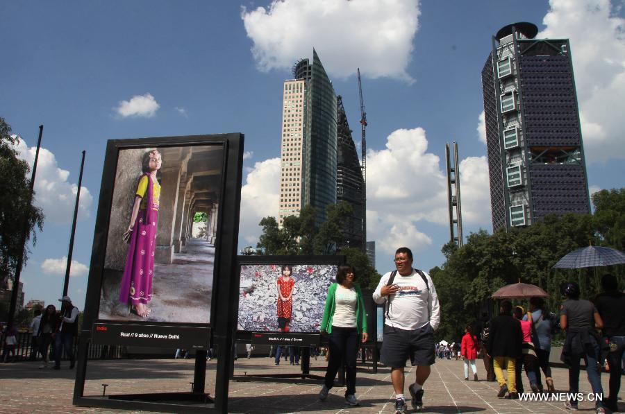  People walk past the photographic show 'Infancia' by Spanish photographer Isabel Munoz, in the Heroic Youth Road of the Forest of Chapultepec, in Mexico City, capital of Mexico, on July 26, 2015.