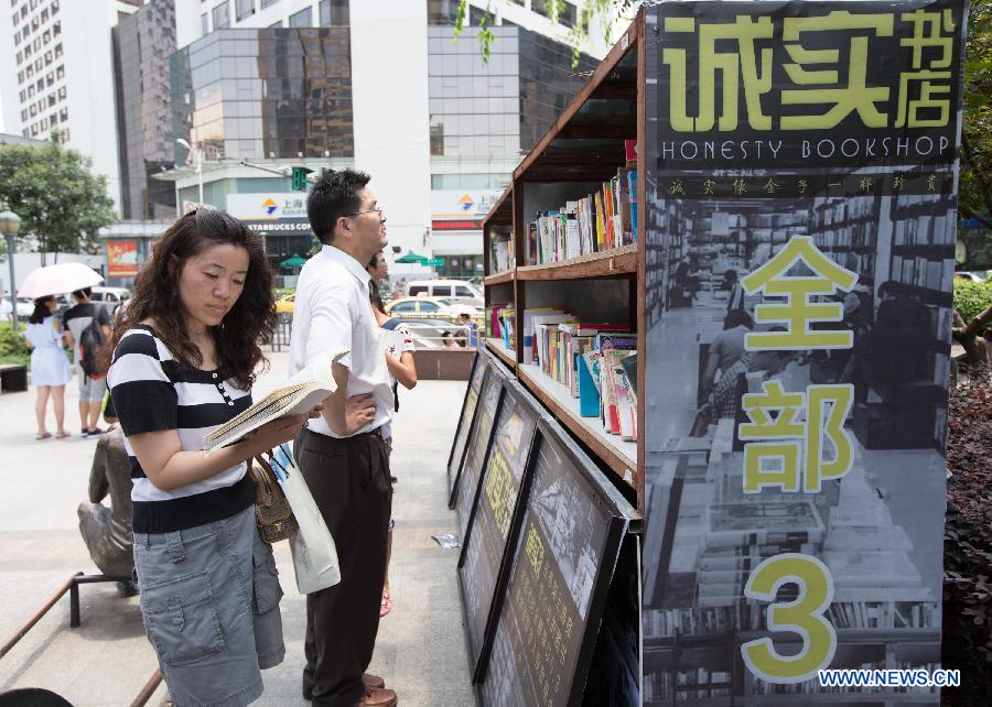 People select books at the Honesty Bookshop in Nanjing, capital of east China's Jiangsu Province, July 28, 2015. The bookshop has no cashier desk and no working staff. Customers purchase books by dropping money into a money box on their own free will. The organizer opened the bookshop to raise the awareness of honesty. (Xinhua/Su Yang)