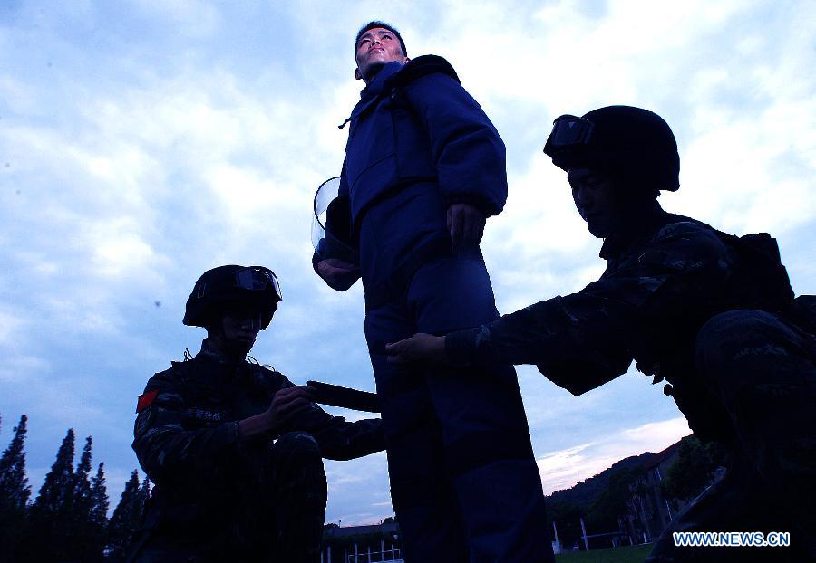 Zhang Yanbiao(C), an Explosive Ordance Disposal(EDO) police, wears a 25-kilogram anti-expolsion suit during a training in east China's Shanghai Municipality, July 30, 2015. EDO police of Shanghai armed police unit continued their training as the heat wave scorched Shanghai. (Xinhua/Chen Fei) 