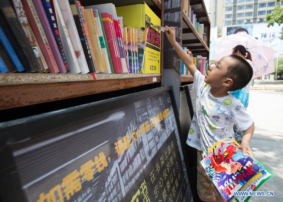 A child drops money into a money box at the Honesty Bookshop in Nanjing, capital of east China's Jiangsu Province, July 28, 2015. The bookshop has no cashier desk and no working staff. Customers purchase books by dropping money into a money box on their own free will. The organizer opened the bookshop to raise the awareness of honesty. (Xinhua/Su Yang)