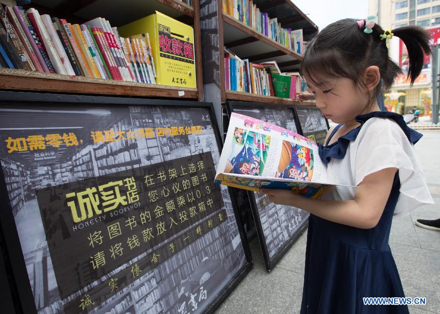 People select books at the Honesty Bookshop in Nanjing, capital of east China's Jiangsu Province, July 28, 2015. The bookshop has no cashier desk and no working staff. Customers purchase books by dropping money into a money box on their own free will. The organizer opened the bookshop to raise the awareness of honesty. (Xinhua/Su Yang)