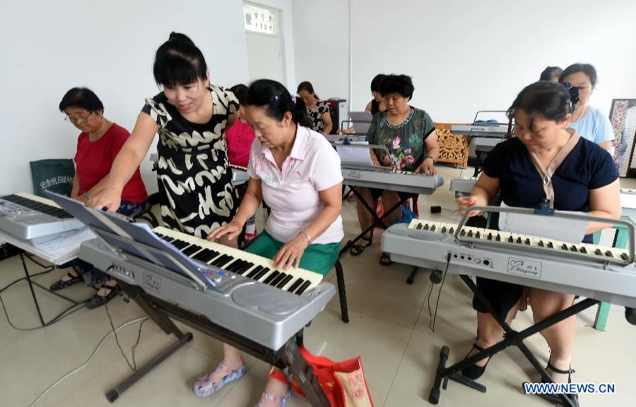 The elderly play electronic keyboards under the guidance of a teacher in Yongqing County, north China's Hebei Province, July 30, 2015. Various free training classes organized by Yongqing Cultural Center have attracted more than 300 seniors and enriched their cultural life. (Xinhua/Li Xiaoguo) 