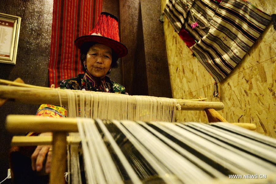 Inheritor An Yu shows how to weave Hezi, a kind of traditional clothing of Yugu ethnic group at a studio in Sunan Yugu Autonomous County of northwest China's Gansu Province, July 30, 2015. Various studios were set by local government this year to preserve and promote Yugu ethnic group's intangible cultural heritages, such as ballads, embroidery and wedding customs. (Xinhua/Chen Bin) 