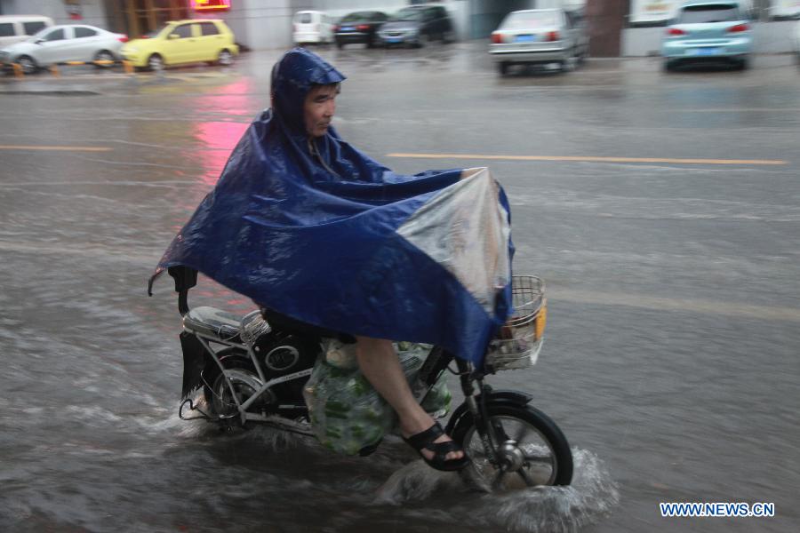 A man rides an electric bike in flood water in Binzhou, east China's Shandong Province, Aug. 3, 2015. 