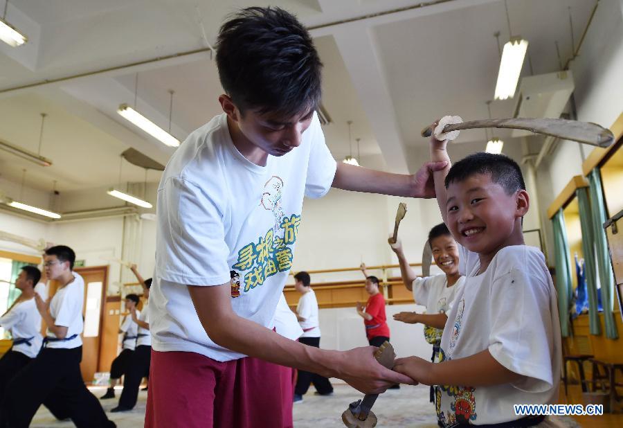 A teacher teaches a little boy the basic movements in traditional Chinese opera in National Academy of Chinese Theatre Arts in Beijing, capital of China, Aug. 4, 2015. 