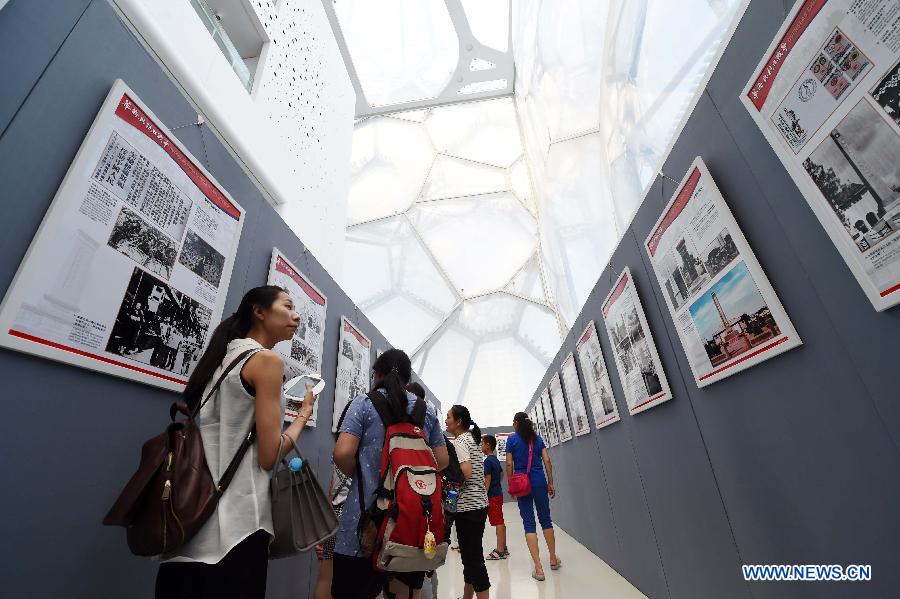 People visit a photo exhibition with the theme of 'Overseas Chinese and the Chinese People's War of Resistance against Japanese Aggression' at National Aquatics Center in Beijing, capital of China, Aug. 4, 2015. 