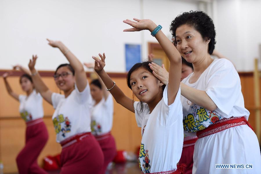 A teacher teaches the youngsters the basic movements in traditional Chinese opera in National Academy of Chinese Theatre Arts in Beijing, capital of China, Aug. 4, 2015. 