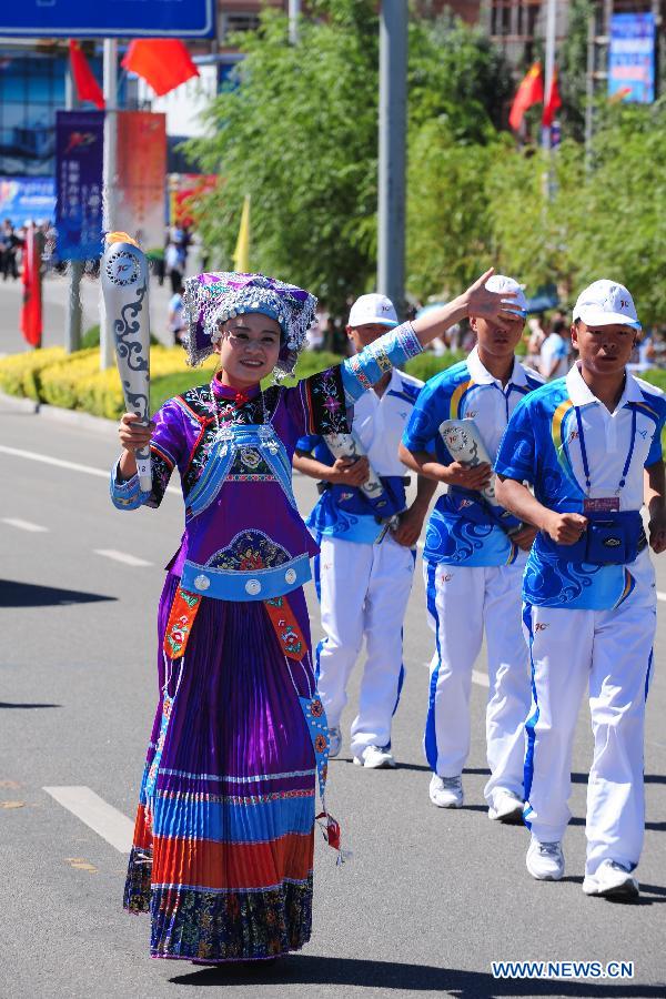 Torch bearer Qin Qing of Buyi ethnic group runs in the torch relay of the 10th Chinese Traditional Games of Ethnic Minorities in Erdos, Inner Mongolia Autonomous Region, China on Aug. 6, 2015.