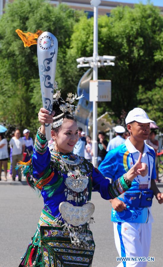 Torch bearer Wu Yanyan of Dong ethnic group runs in the torch relay of the 10th Chinese Traditional Games of Ethnic Minorities in Erdos, Inner Mongolia Autonomous Region, China on Aug. 6, 2015. 