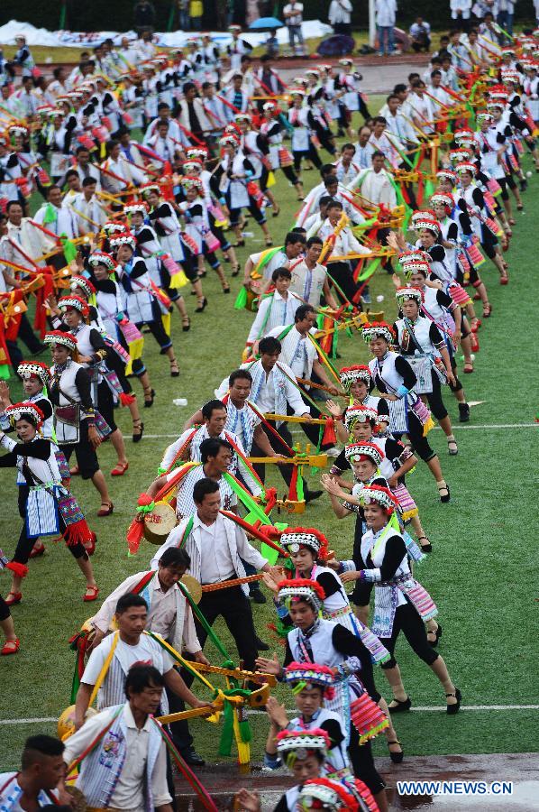 Axi people, a branch of the Yi ethnic group, perform their folk dance named 'Axi Tiaoyue', or 'Axi Dance under Moonlight', in the stadium of Mile, southwest China's Yunnan Province, Aug. 7, 2015.