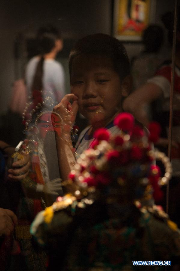 A boy views a silk figurine during an exhibition in Beijing, capital of China, Aug. 7, 2015.