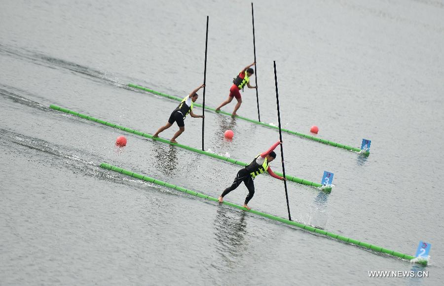 Athletes compete in a women's intermediary heat of single bamboo drifting, a specialty in southwest China's Guizhou Province, during the 10th National Traditional Games of Ethnic Minorities of China in Ordos, north China's Inner Mongolia Autonomous Region, Aug. 10, 2015.