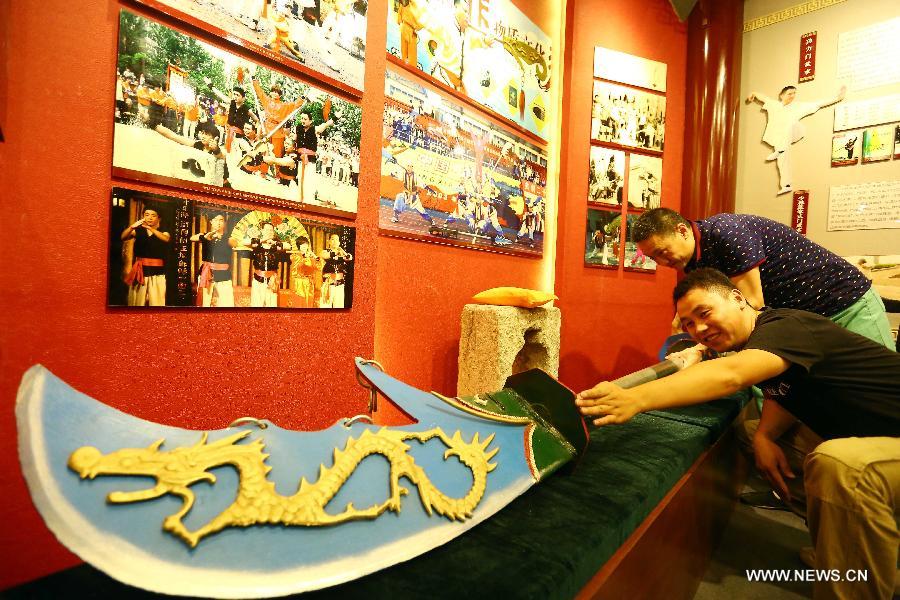 Visitors touch an ancient sword at the new exhibition hall of intangible cultural heritage in Hongqiao District of Tianjin, north China, Aug. 11, 2015. 