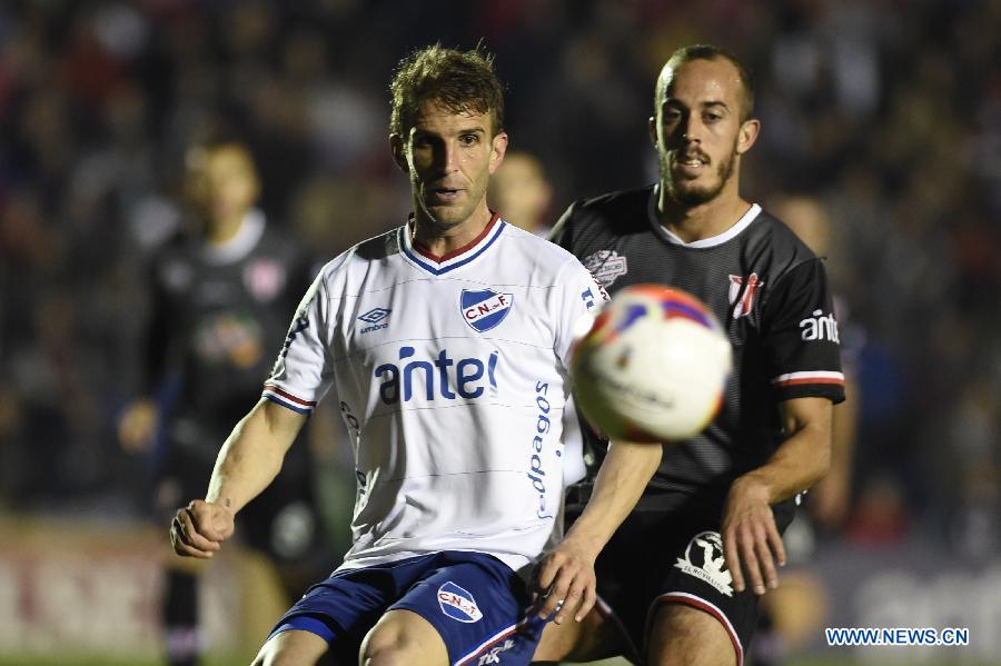 Nacional's Ivan Alonso (L) vies the ball with Villa Teresa's Jonathan Souza Motta (L) during their match on day 1 of the Opening Tournament of the Uruguyan Soccer Championship, held in the Gran Parque Central stadium, in Montevideo, capital of Uruguay, on Aug. 15, 2015.