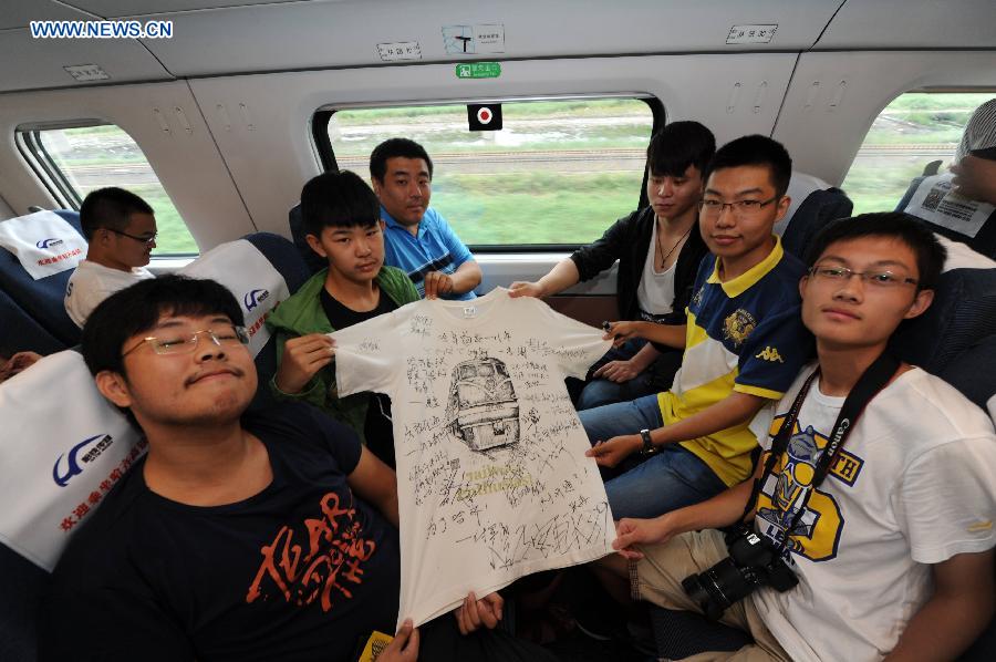 Passengers pose for a group photo on the high-speed train D7989, northeast China's Heilongjiang Province, Aug. 17, 2015.