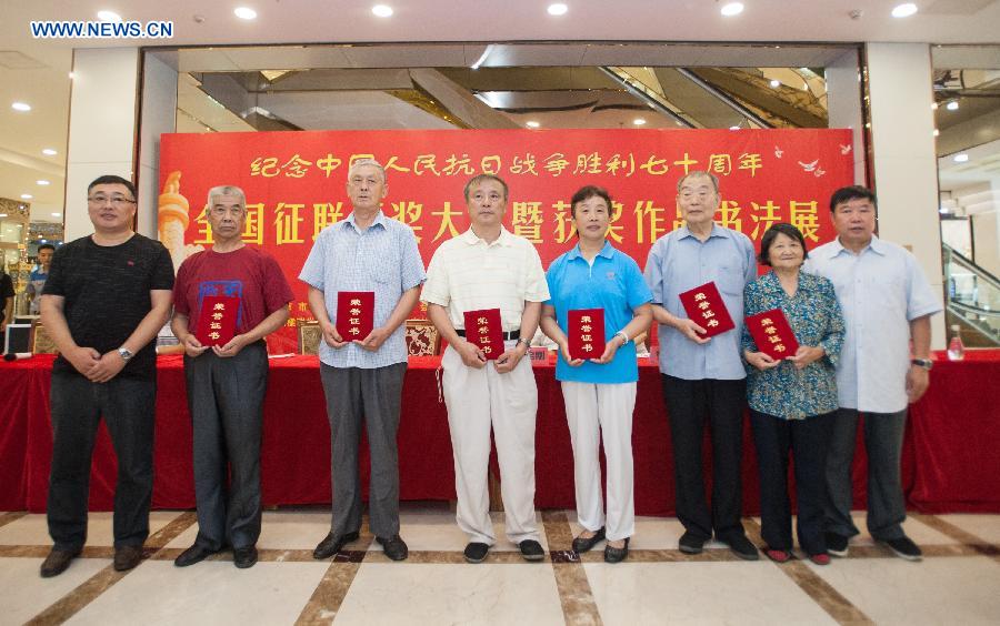 Award-winning exhibitors pose for a group photo at a calligraphy exhibition in Beijing, capital of China, Aug. 17, 2015. 