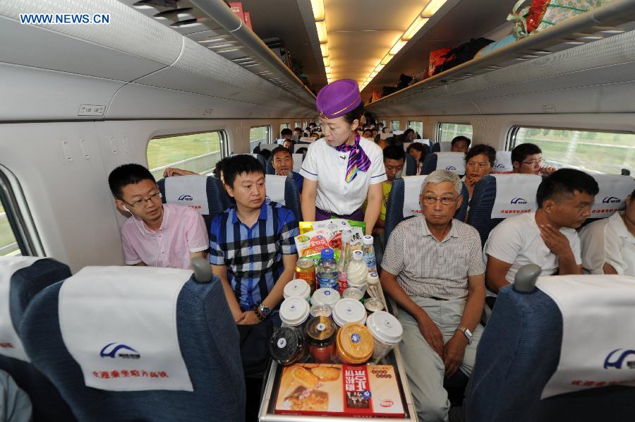 A stewardess serves passengers on the high-speed train D7989, northeast China's Heilongjiang Province, Aug. 17, 2015. 