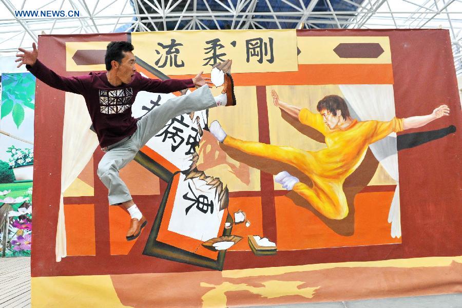 A man poses for photos during an exhibition of 3D trick art in Lhasa, capital of southwest China's Tibet Autonomous Region, Aug. 20, 2015.