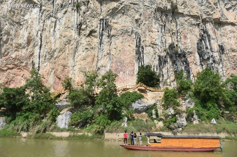 Tourists view Huashan rock paintings on the cliffs along the Mingjiang River, a tributary of the Zuojiang River, in Ningming County of Chongzuo City, southwest China's Guangxi Zhuang Autonomous Region, Aug. 20, 2015. 