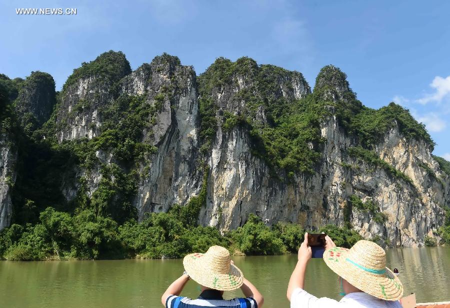 Tourists view Huashan rock paintings on the cliffs along the Zuojiang River in Longzhou County of Chongzuo City, southwest China's Guangxi Zhuang Autonomous Region, Aug. 21, 2015.