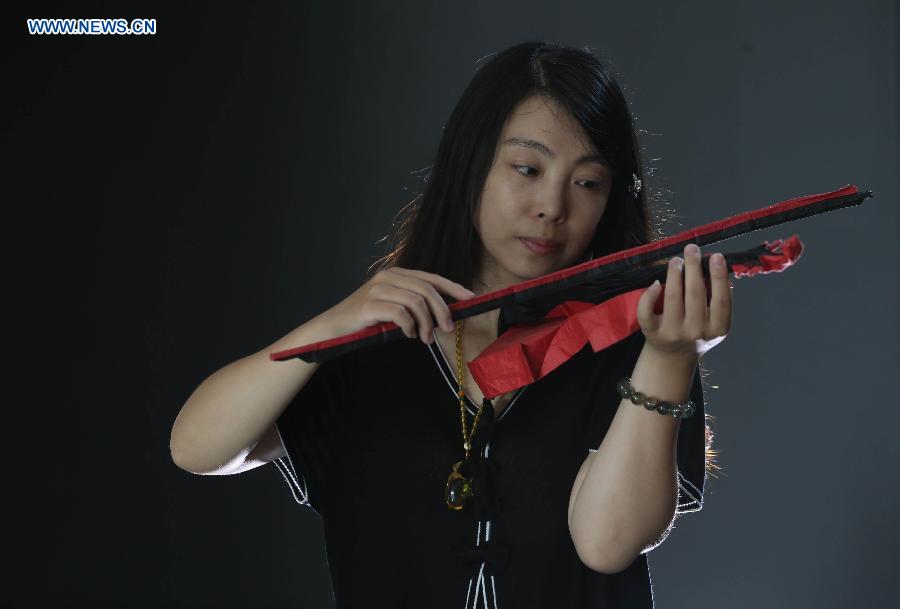 A citizen plays a paper voilin made by Qin Kun in Guilin, south China's Guangxi Zhuang Autonomous Region, Sept. 6, 2015.