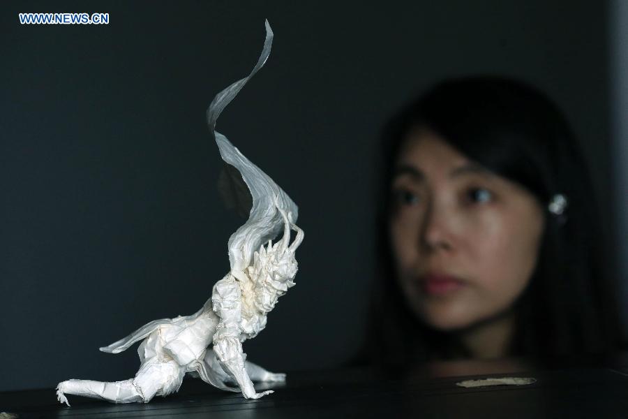 A citizen looks at an origami works made by Qin Kun in Guilin, south China's Guangxi Zhuang Autonomous Region, Sept. 6, 2015. 