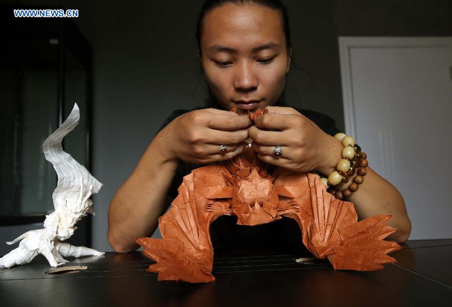 Qin Kun makes his origami works in the pattern of owl in Guilin, south China's Guangxi Zhuang Autonomous Region, Sept. 6, 2015.