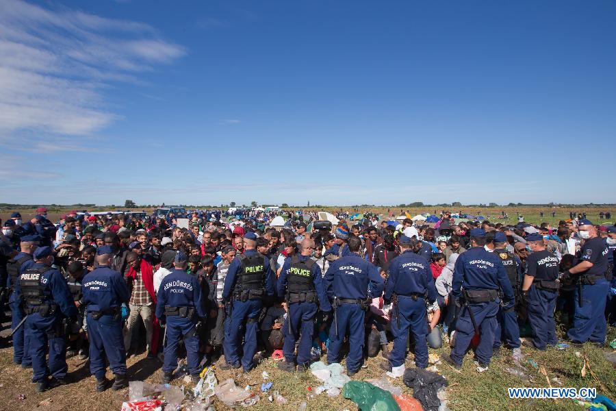 Hungarian police officers stand guard at a gathering point of illegal migrants near Roszke, a village on the Serbian-Hungarian border, Hungary, on Sept. 7, 2015.