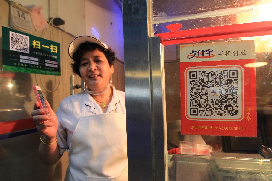 A stall owner shows her QR code for online payment at a market in Wenzhou, east China's Zhejiang Province, Sept. 14, 2015.