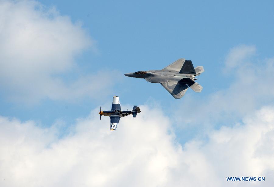 An F-22 Raptor (up) and a P-51 Mustang perform during an air show at Andrews Air Base outside Washington D.C. in Maryland, the United States, Sept. 19, 2015. 