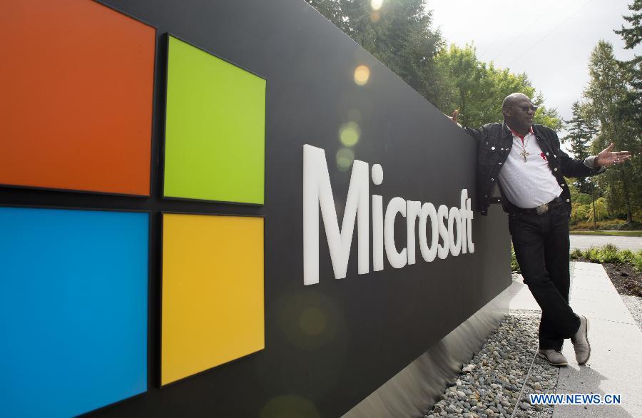 A visitor poses for a photo with Microsoft's logo at Microsoft's corporate headquarters in Redmond, Washington State, the United States, Sept. 19, 2015.