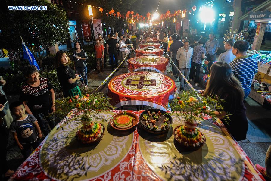 Local residents arrange a street-long banquet, presenting traditional pastries and dishes, to celebrate the coming Mid-Autumn Festival in Tangxi Town of Hangzhou, east China's Zhejiang Province, Sept. 24, 2015. 