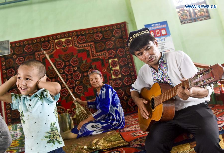 Pataer Keyimu plays guitar at home in the Grape Valley of Turpan, northwest China's Xinjiang Uygur Autonomous Region, Sept. 6, 2015. 