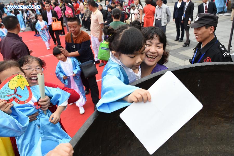 Children put wish cards in a cauldron during a first writing ceremony in Guiyang, capital of southwest China's Guizhou Province, Sept. 28, 2015. 