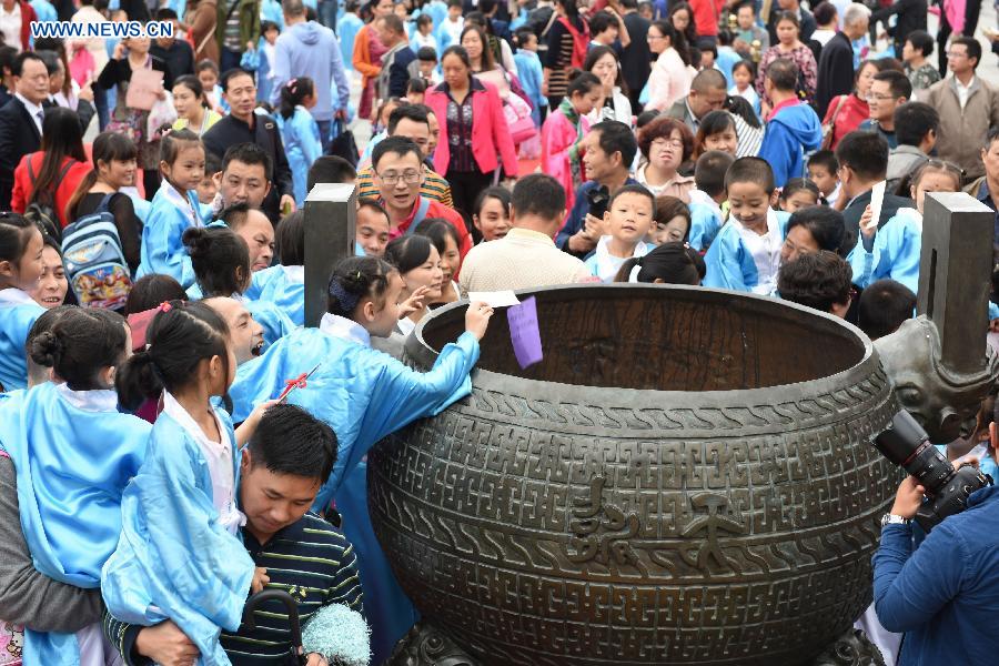 Children put wish cards in a cauldron during a first writing ceremony in Guiyang, capital of southwest China's Guizhou Province, Sept. 28, 2015. 