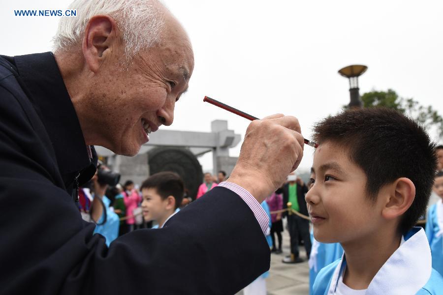 A boy gets a red dot on his forehead (which is called opening the wisdom eye) during a first writing ceremony in Guiyang, capital of southwest China's Guizhou Province, Sept. 28, 2015.