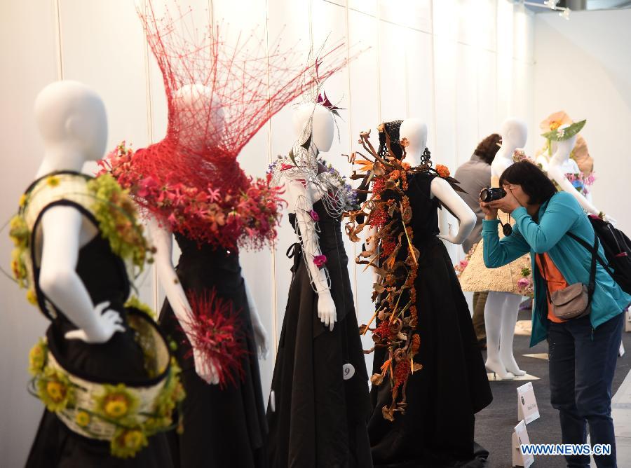 A woman takes pictures of floral designs on people's dressing at the 2015 Taipei International Flower Design Award show in Taipei, southeast China's Taiwan, Oct. 31, 2015. 