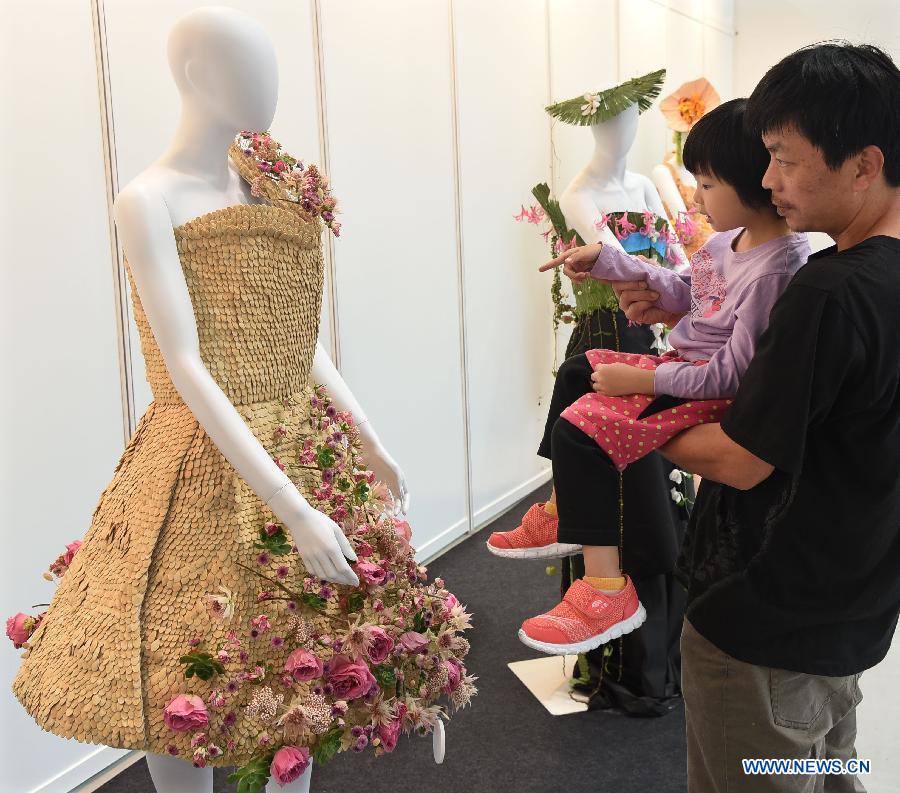 Local residents look at a floral design on people's dressing at the 2015 Taipei International Flower Design Award show in Taipei, southeast China's Taiwan, Oct. 31, 2015.