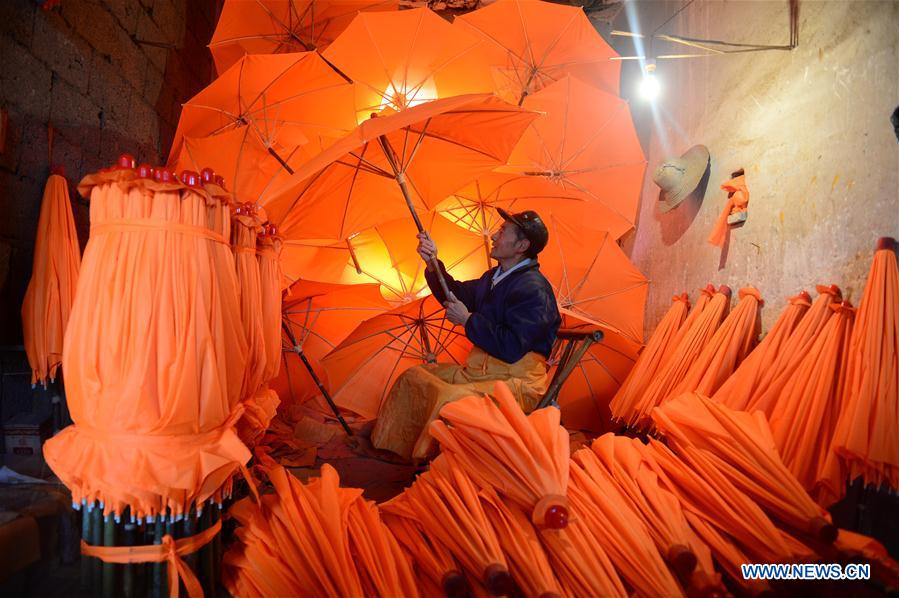 A worker checks the newly-made oilcloth umbrellas at a plant in Gufeng Village of Jingxian County, east China's Anhui Province, Dec. 3, 2015. The umbrella, made of oiled cloth and bamboo frame, is a traditional Chinese handicraft. 