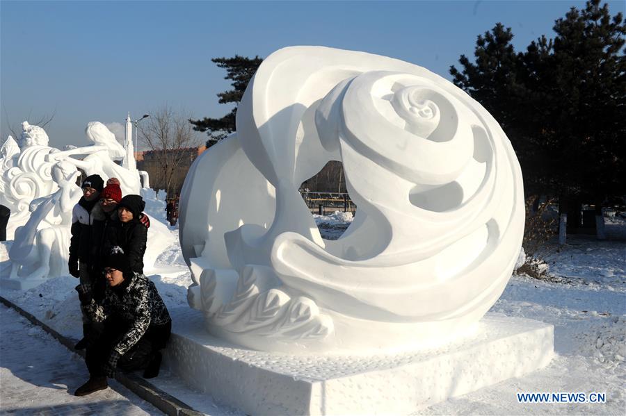 Tourists pose for photos with a snow sculpture of the 8th International Snow Sculpture Contest for College Students in Harbin, capital of northeast China's Heilongjiang Province, Jan. 7, 2016. 