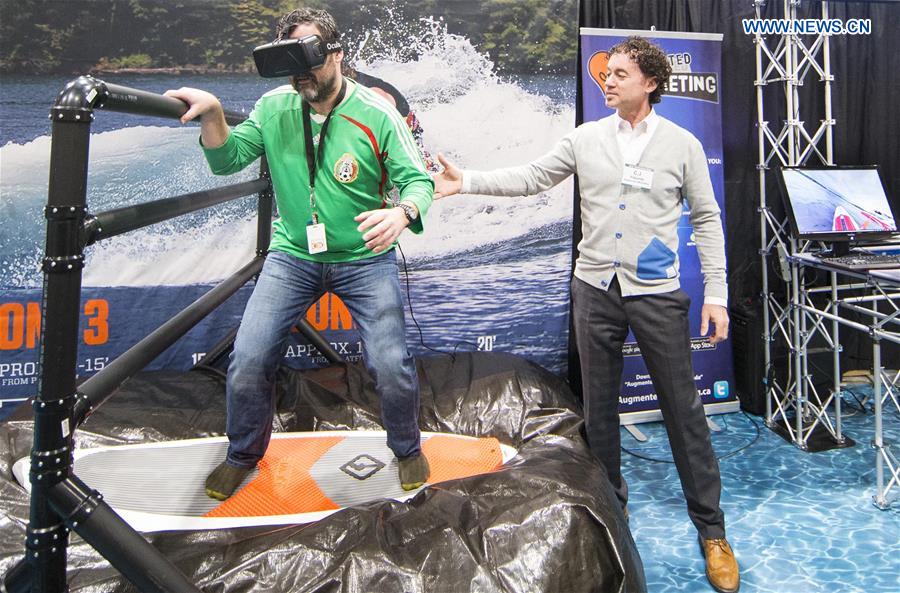 A visitor (L) takes a practice of the sailing simulator during the 2016 Toronto International Boat Show at Exhibition Place in Toronto, Canada, Jan. 8, 2016. 