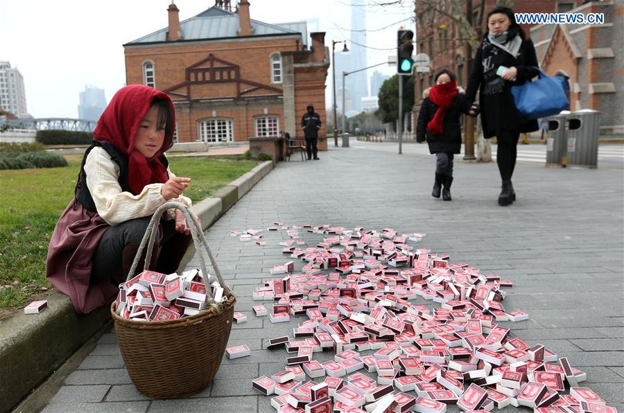 A 'little match girl' sits with matches before her at Waitan area in Shanghai, east China, Jan. 12, 2016. 