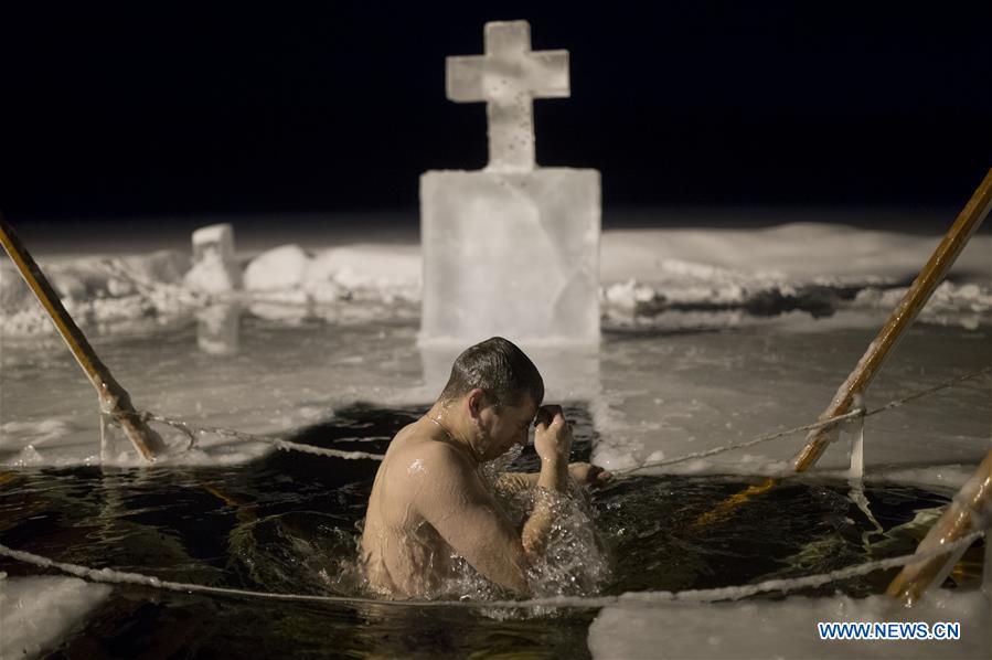 VALDAY, Jan. 19, 2016 (Xinhua) -- A Russian Orthodox believer bathes in the icy water on Epiphany in Valday lake near Iversky monastery with the air temperature at about 10 Celsius degrees below zero, in Valday, Russia, Jan. 19, 2016. Orthodox believers mark Epiphany on Jan. 19 by immersing themselves in icy waters regardless of the weather. The water is blessed by a cleric and considered pure. (Xinhua/Pavel Bednyakov) 