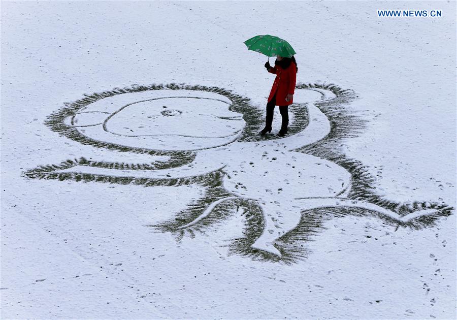 A teacher draws a monkey on snow-covered ground at the No. 2 Middle School of Xuyi County, east China's Jiangsu Province, Jan. 21, 2016.