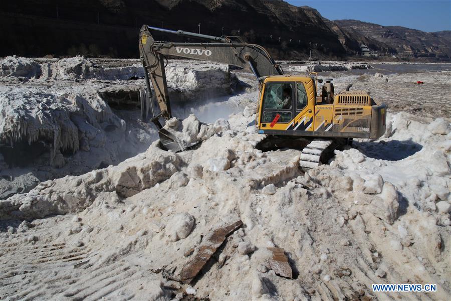 An excavator cleans away ice at the Hukou Waterfall of the Yellow River in Jixian County, north China's Shanxi Province, Feb. 16, 2016. 